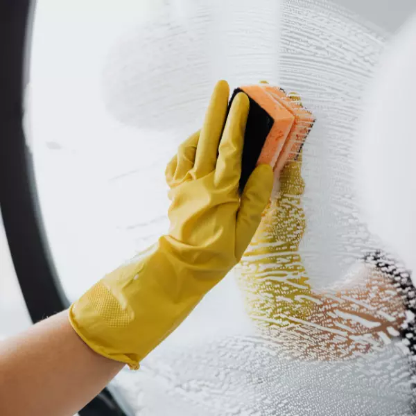 Close up of woman wearing Yellow glove cleaning mirror
