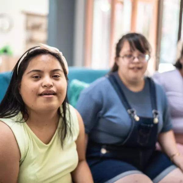 Disabled friends sitting on couch and smiling at camera together