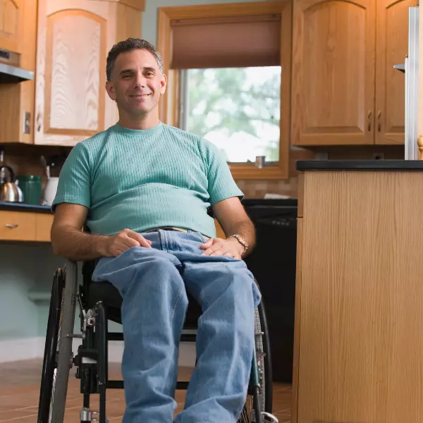 Smiling man in wheelchair in kitchen looking at the camera
