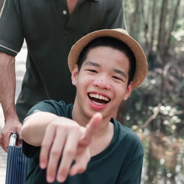 Disabled boy smiling and pointing at camera